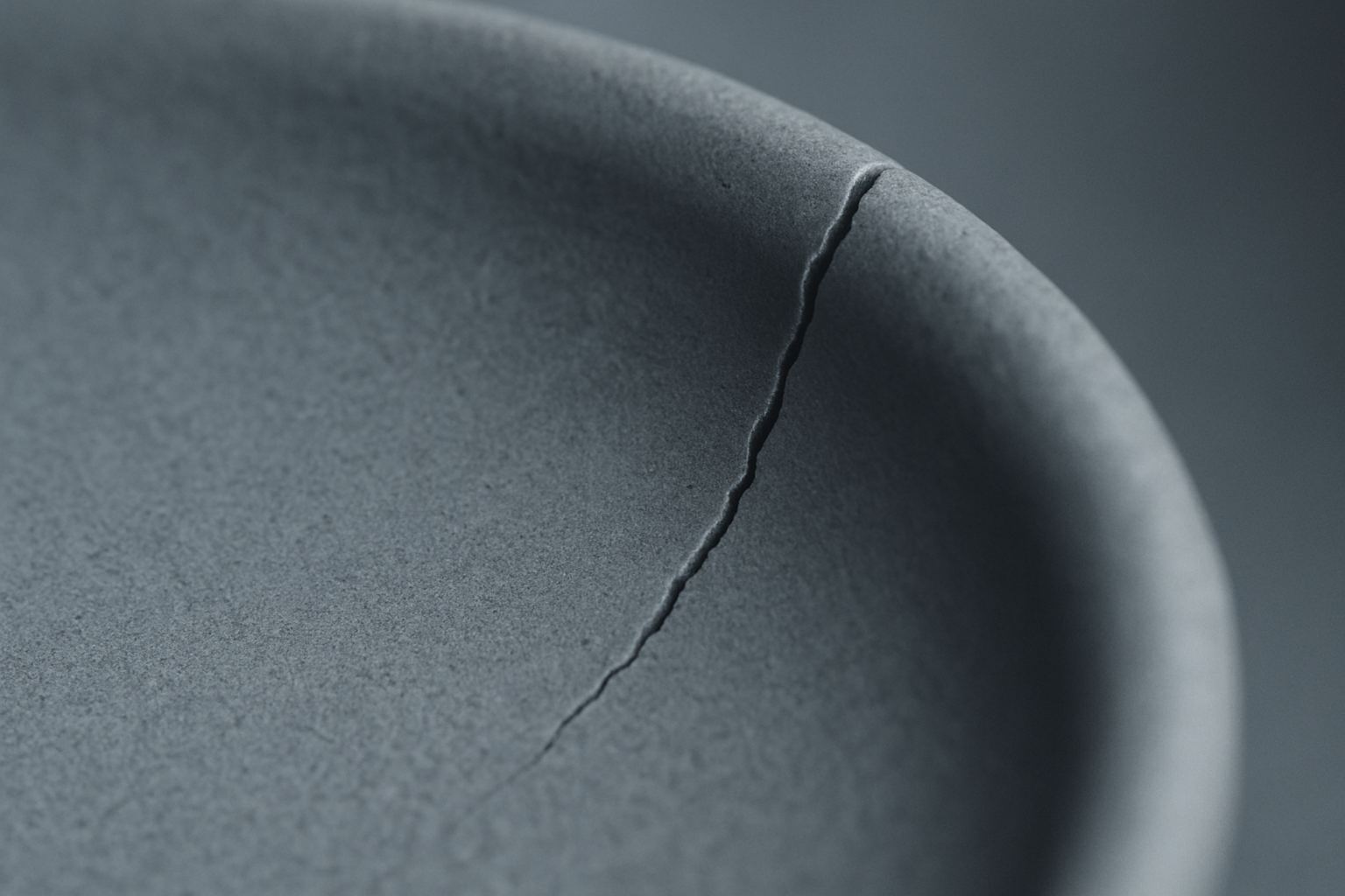 A matte surface splitting at an edge. Thin material under repeated tension fails at the corners.